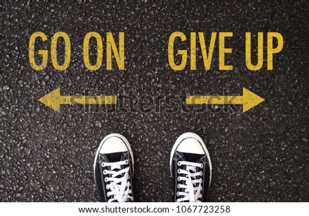 Black shoes standing at the road with go on and give up wording. Royalty-Free Stock Photo #1067723258