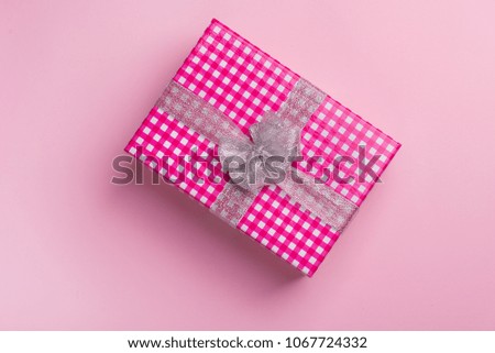 Gift box with a gray bow on a pink background