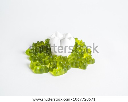 The tooth is surrounded by sweets on the white background