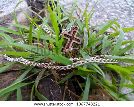 Strength golden christian cross necklace on natural green grass, selective focus