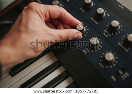 Man hand controlling musical keyboard synthesizer  buttons while playing music.