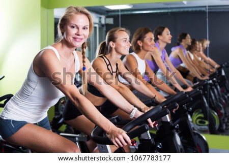 Young athletic women cycling on stationary bike in fitness club