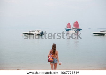 rear view of woman holding cocktail and looking at yachts in ocean