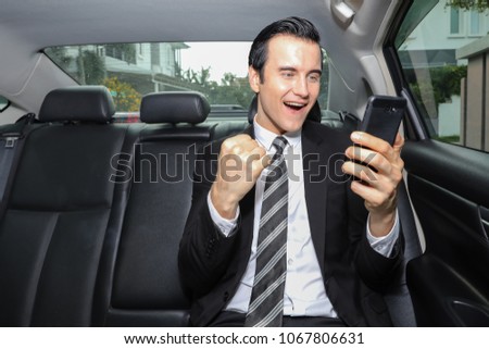 Portrait of happy handsome businessman in suit yelling at mobile phone after recieved good news in luxury car. Achived target, business concept. Achivement concept.