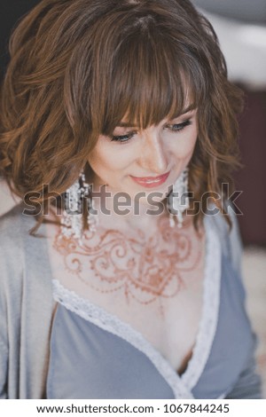 Portrait of a pregnant girl with a painted henna pattern necklace.