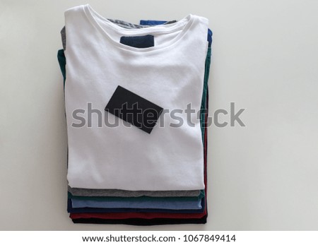 Top view of color T-Shirt with black business card on white background.