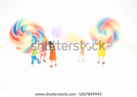 Miniature people: Group of children playing on white background and sweets candies with copy space using as education, boy and girl, children's day concept.