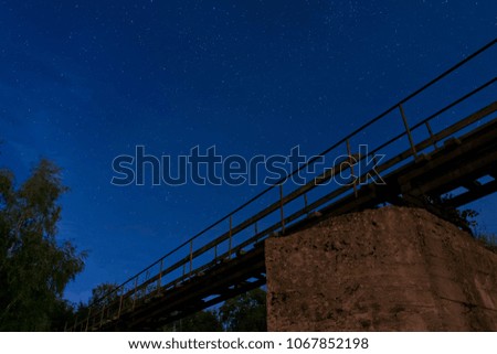 Night sky with many stars before sunrise. View from under the old bridge.