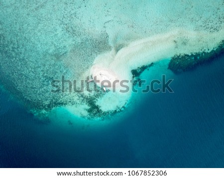Aerial picture of Tiny sandbar island in the middle of transparent blue ocean