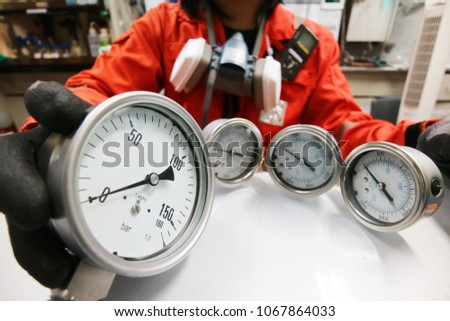 Instrument technician is fixing pressure guages. Engineer check and repair pressure guages on the table.