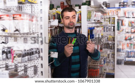 Glad fisherman choosing fishing lures for fishing in the sports shop