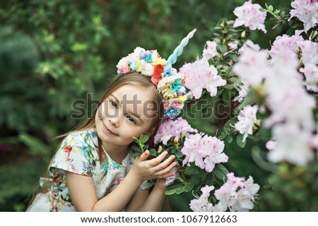 Fantasy little girl with rainbow unicorn horn with flowers in azalea park. for Halloween.