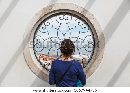 Girl looking from the Circle window - Santa Luzia viewpoint (miradouro), with view to Alfama old town and Tagus river - Lisbon, Portugal
