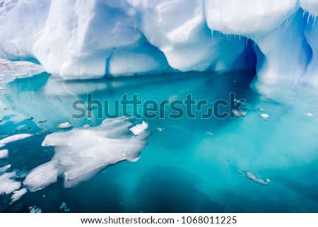 Small ice chunks float near a large iceberg surrrounded by torqu
