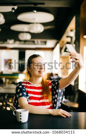 Happy young woman taking selfie on smartphone wearing short with colors of american flag