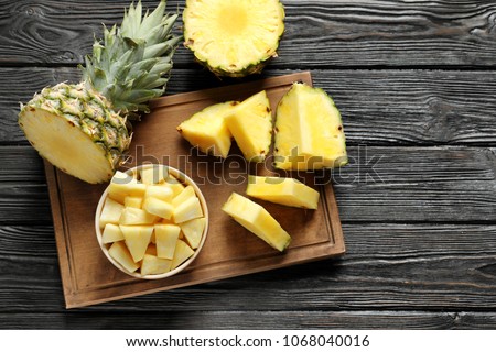 Wooden board with fresh sliced pineapple on table, top view Royalty-Free Stock Photo #1068040016