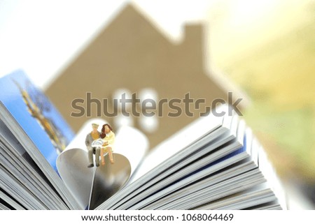 Miniature couple sitting on the heart made from open book us as love , invest in education and married life.