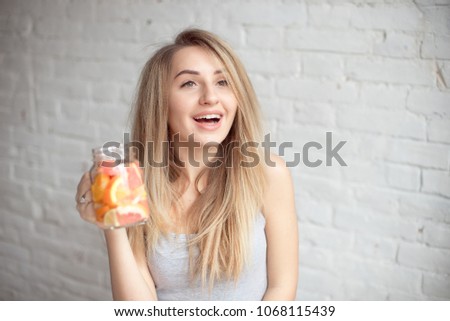 Close-up happy woman with glass of fresh summer lemonade with straw. Caucasian young girl 20-25 years old indoors against brick wall background.