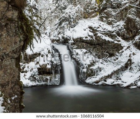 Waterfall on long exposure in winter with snow, Schwarzwald forest, Germany