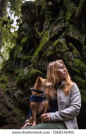 Woman holiding a small dog, Chihuahua, in her arms surrounded by beautiful nature. Taken in Lynn Valley, North Vancouver, British Columbia, Canada.