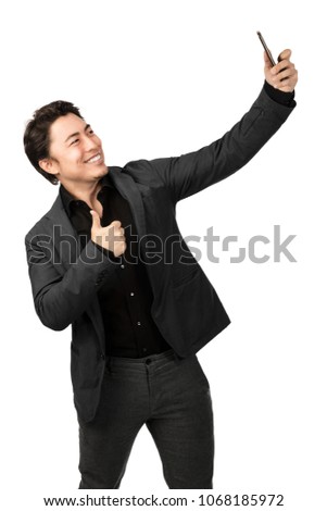 Smiling happy man taking a selfie with his phone and doing thumbs up. White background.