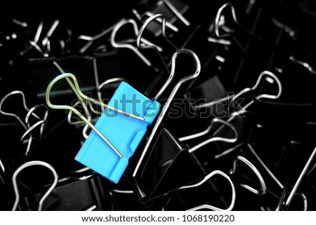 A blue color binder clip ,multi binder paper clip backgtound in black and white style.