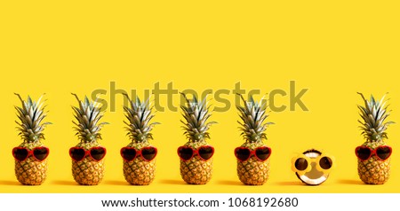 Series of pineapples and a coconut wearing sunglasses on a yellow background Royalty-Free Stock Photo #1068192680