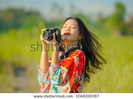 sweet young Asian Chinese or Korean woman on her 20s taking picture with photo camera smiling happy in beautiful nature landscape in holidays and photographer hobby concept