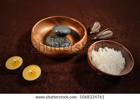 Wellness brown background stock images. Spa still life images. Wellness setting. Sea salt in bowl, lava stones and candles on a brown textured background