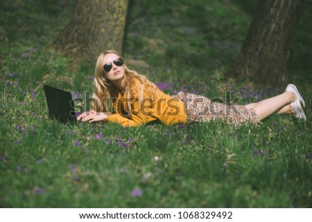 blond woman with a laptop in the park on the grass
