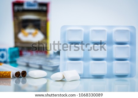 Nicotine chewing gum in blister pack on blurred background of cigarette pack.  Medicine for giving up smoking. World no tobacco day concept. Royalty-Free Stock Photo #1068330089
