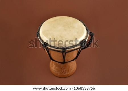 African drum stock images. Wooden drum with goat skin, ethnic musical instrument. Djembe Drum on a brown background