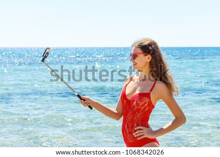 Summer beach vacation girl taking fun mobile selfie photo with smartphone. Girl wearing red sunglasses posing for selfie.
