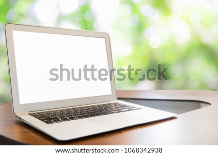Laptop with blank screen on tablewith Defocus nature green bokeh, abstract nature background with green leaves and bokeh lights.