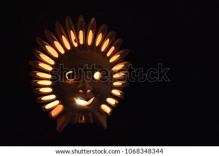 Ceramic Sun Face stock images. Glowing lamp on a dark background. Ceramic sun on a brown background. Ceramic Sun Lamp. Sun clay lamp