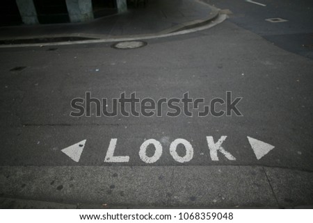 White written looking left and right warning sign on the pedestrians footpath surface in Sydney city CBD, Australia

