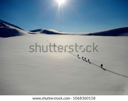 A group of tourists climbs to a snow-covered mountain pass in winter in Kamchatka