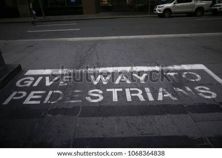 White written give away to pedestrians warning on the pedestrians footpath surface in Sydney city CBD, Australia
