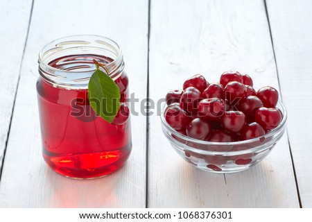 Homemade fresh cherry juice in a glass and fresh cherries on white wooden table