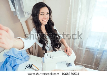 . beautiful woman seamstress with long hair does selfie. tailor creates a collection of clothes on the background of a sewing machine. concept of online sewing education