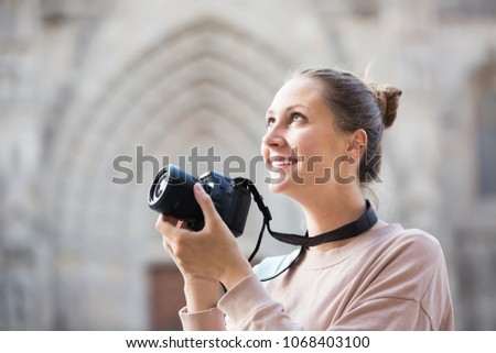 Cheerful woman  taking picture with camera in the town 