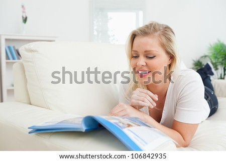 Casual woman lying on a sofa and reading a booklet