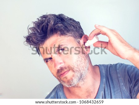man using ear drops on gray background