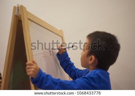 Child learning and sketching in classroom or nursery.