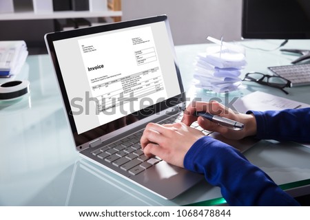 Close-up Of A Businessperson's Hand Analyzing Invoice On Laptop At Workplace Royalty-Free Stock Photo #1068478844