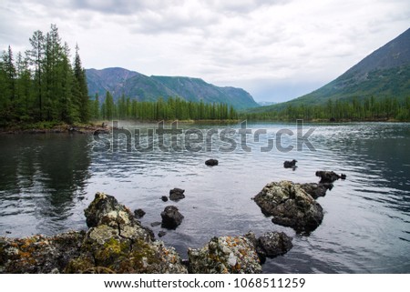 Wonderful lake wide panorama. Scenic summer landscape, mountains and blue cloudy sky at background. Eastern Sayan, Buryatia, Russia.