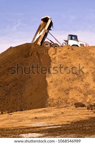 Construction truck tipping dumping raw earth soil on site