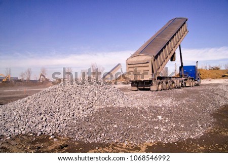 Construction truck tipping dumping gravel on road construction site