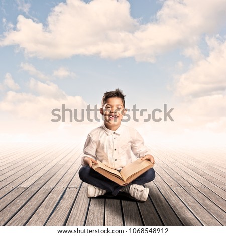 little boy reading a book on a wharf