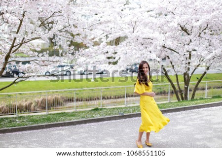 Asian girl wearing beautiful yellow dress at park with windy hair